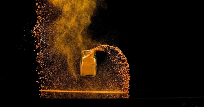 Turmeric (curcuma longa), Powder into a small jar falling against Black Background, Indian Spice, by Lacz Gerard