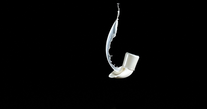 Glass of Milk Bouncing and Splashing on Black Background, by Lacz Gerard