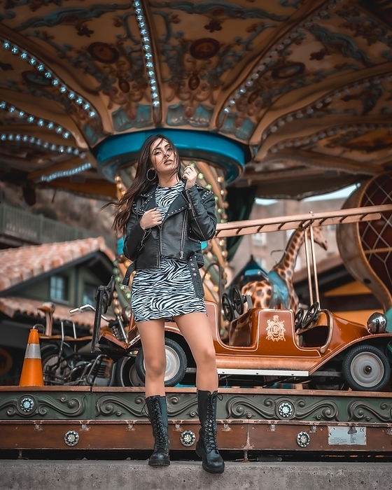 Street style, sexy Caucasian brunette in a carousel at the fair with short skirt and a leather jacket, by Unai Huizi