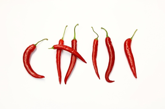 Red chilli peppers arranged to spell out RED HOT CHILI . The chillies are against a white background, by fotoping