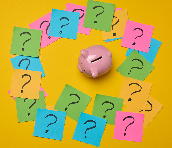 Ceramic piggy bank and stickers with drawn question marks on a yellow background, top view Ceramic piggy bank and stickers with drawn question marks on a yellow background, top view