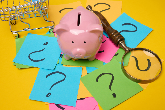 Ceramic piggy bank and stickers with drawn question marks on a yellow background, top view Ceramic piggy bank and stickers with drawn question marks on a yellow background, top view