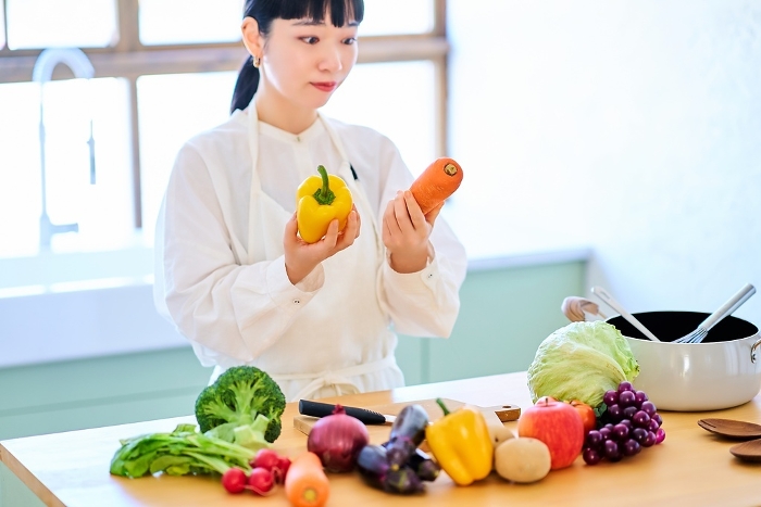 A young Japanese woman holding vegetables in her kitchen (People)