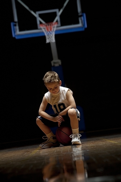 Young Boy Sitting On Basketball Court Looking Solemn, by Ron Nickel / Design Pics