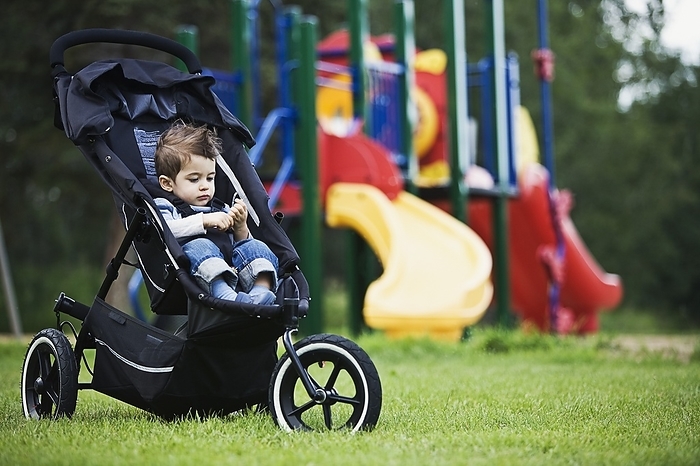 Young Boy In Stroller In Park Playground, by Daniel Sicolo / Design Pics
