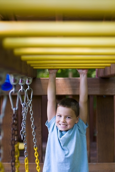 Young Boy Having Fun Playing On Jungle Gym Swing Set, by Craig Craver / Design Pics
