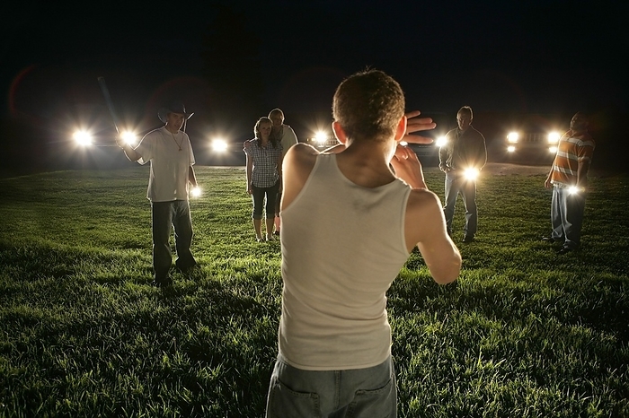 Young Man Outdoors At Night Surrounded By People With Flashlights, by Ron Nickel / Design Pics