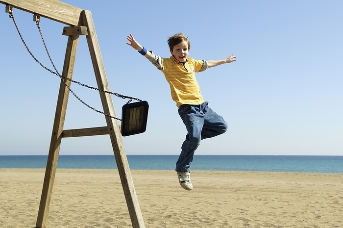 Boy Jumping Off Swing At Beach, by Ben Welsh / Design Pics