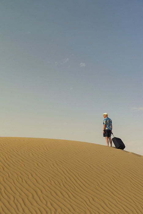 UAE Dubai Barefoot Man With Suitcase On Sand Dune  Dubai, United Arab Emirates, by Ian Cumming   Design Pics