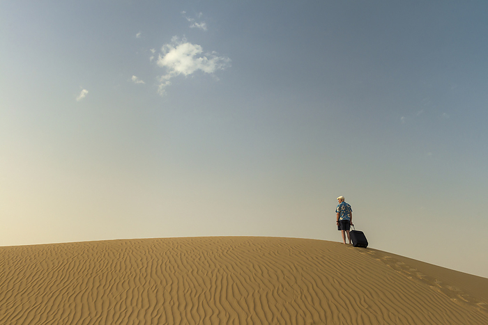 UAE Dubai Barefoot Man With Suitcase On Sand Dune  Dubai, United Arab Emirates, by Ian Cumming   Design Pics