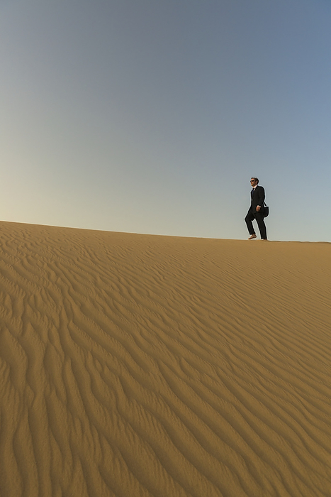 UAE Dubai Man In Smart Suit Walking Along Top Of Sand Dune At Dusk  Dubai, United Arab Emirates, by Ian Cumming   Design Pics