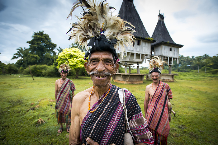 Group Of Men In Traditional Attire With Sacred Houses In The Background; Lospalmos District, Timor-Leste, by David Kirkland / Design Pics
