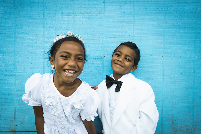 Children Dressed In White Formal Wear Against A Blue Wall; Hapai Island, Tonga, by David Kirkland / Design Pics