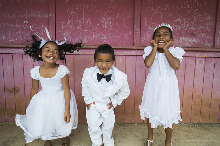 Children Dressed In White Formal Wear Against A Red Wall; Hapai Island, Tonga, by David Kirkland / Design Pics