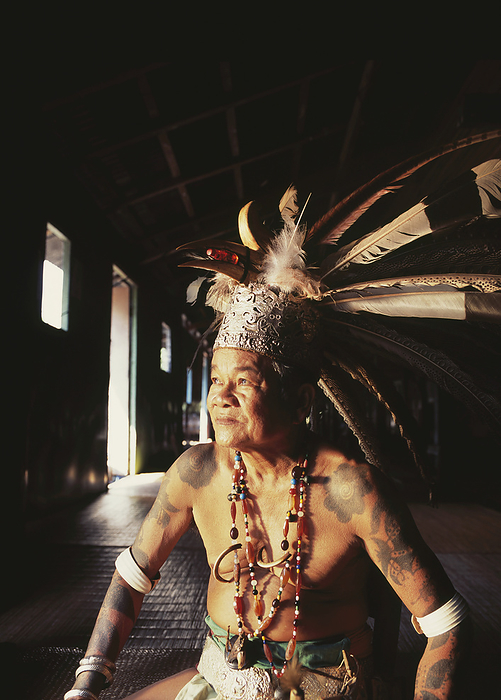 Village Chief Sitting In A Long House In Traditional Dress; Sarawak, by David Kirkland / Design Pics