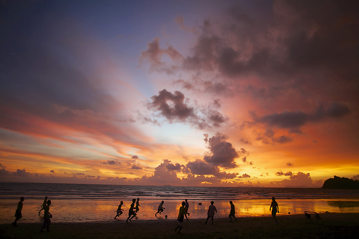 Silhouette Of People Playing Soccer At The Water's Edge With A Dramatic Sunset, by Ian Taylor / Design Pics