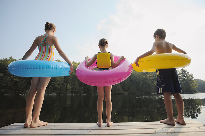 Canada Kids Standing At End Of Dock Holding Inflatable Rings On Crystal Lake  Ontario, Canada, by Vast Photography   Design Pics