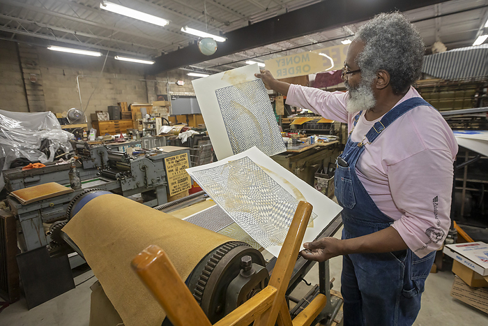 Man working in printing shop Man working in a letterpress printing shop. Amos Kennedy prints posters and gives workshops on letterpress printing. Photographed in Detroit, Michigan, USA., by JIM WEST SCIENCE PHOTO LIBRARY