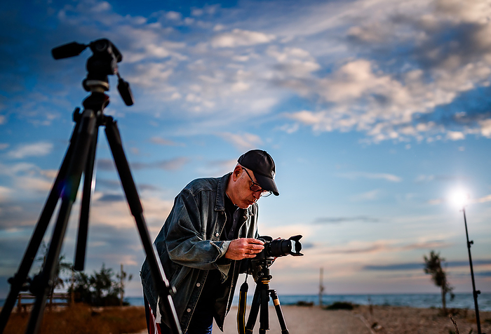 Man taking photographs at sunset., by Cavan Images / Lazareto