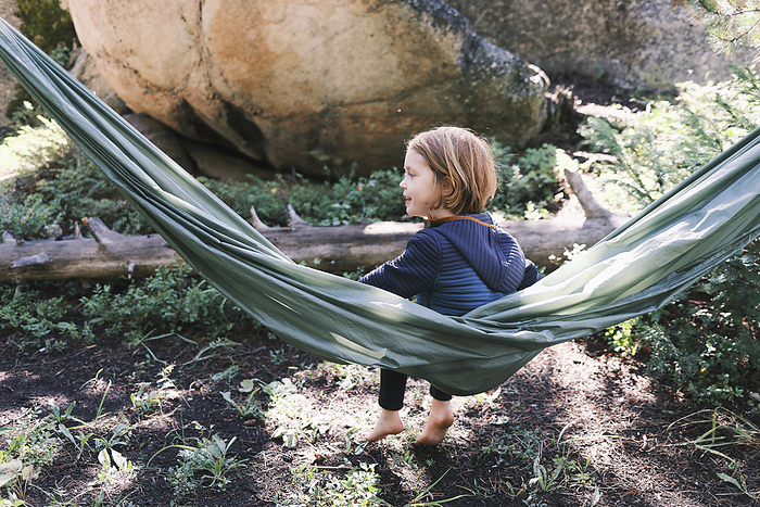 Young girl relaxing outdoors on a hammock, by Cavan Images / Patrick Lienin