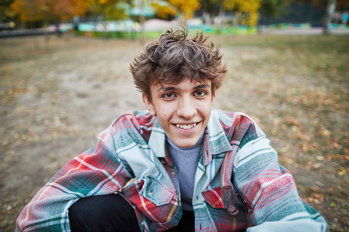 portrait of a smiling young man in the park, by Cavan Images / Elena Perevalova