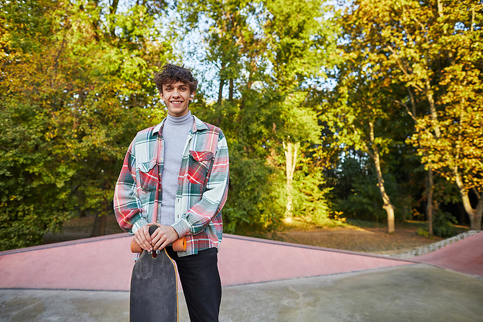 smiling young man with longboard in skate park, by Cavan Images / Elena Perevalova