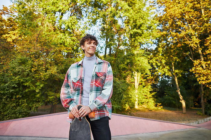 smiling teenager with longboard in skate park, by Cavan Images / Elena Perevalova