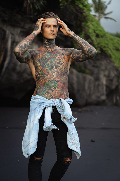 Young charming handsome tattooed man with a naked torso., by Cavan Images / Yuliya Kirayonak