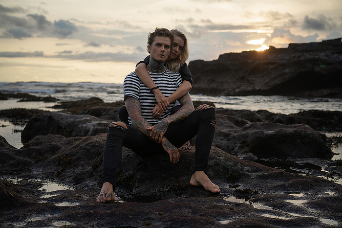 Couple in love on the beach watching the sunset, Bali. Tattooed man., by Cavan Images / Yuliya Kirayonak