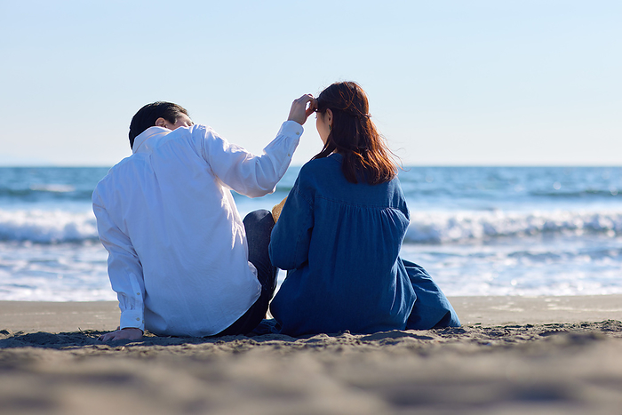 Back view of a Japanese couple relaxing on the beach