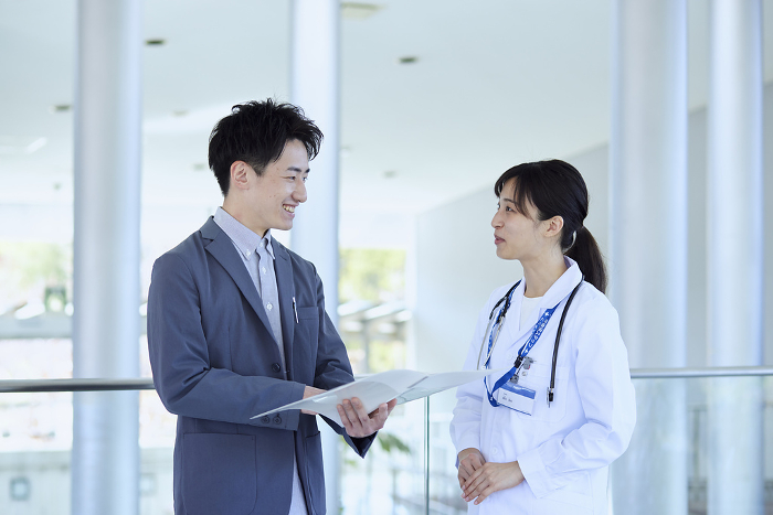 A Japanese female doctor talking with a MR man in a suit in a hospital (People)
