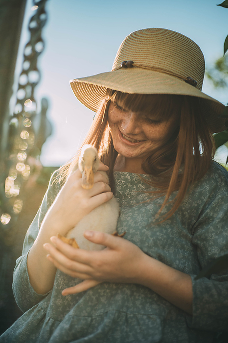 Smiling young woman with freckles holding duckling