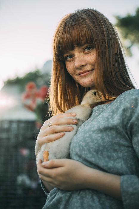 Young woman with freckles holding duckling