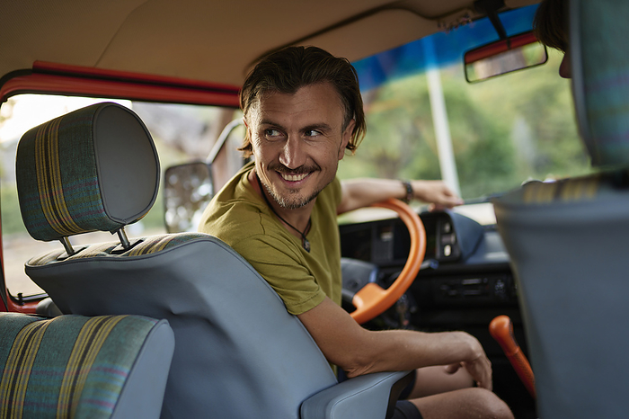 Smiling mature man sitting on driver's seat inside motor home