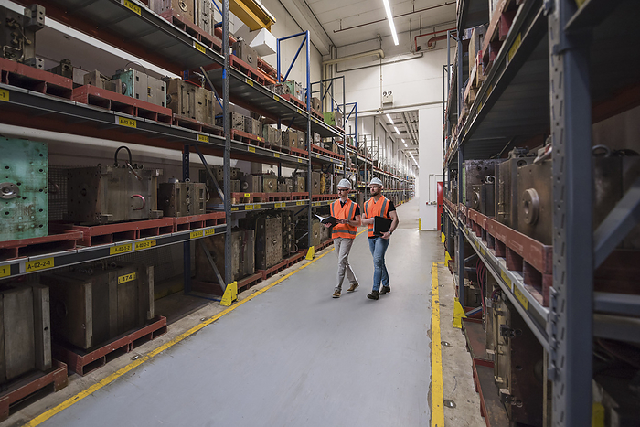 Colleagues examining shelves at warehouse in factory