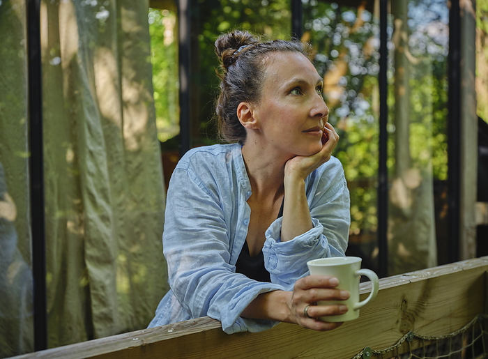 Thoughtful mature woman enjoying coffee on porch
