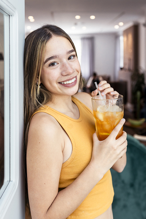 Smiling woman holding glass of iced tea at home