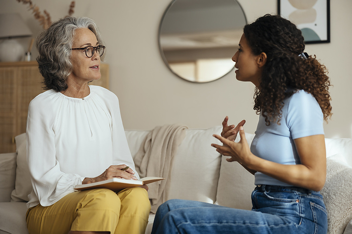 Woman talking to psychologist on sofa at home