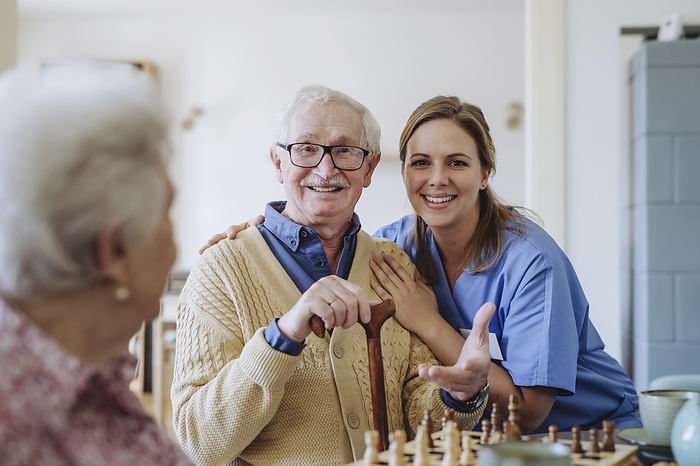 Smiling healthcare worker with senior man and woman at home