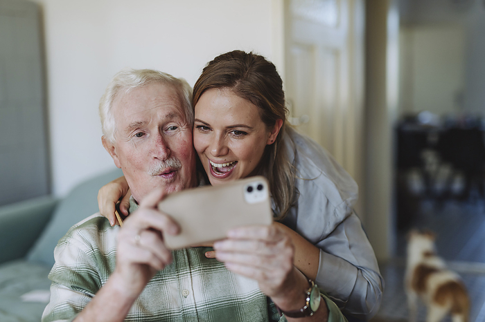 Happy healthcare worker with senior man taking selfie at home