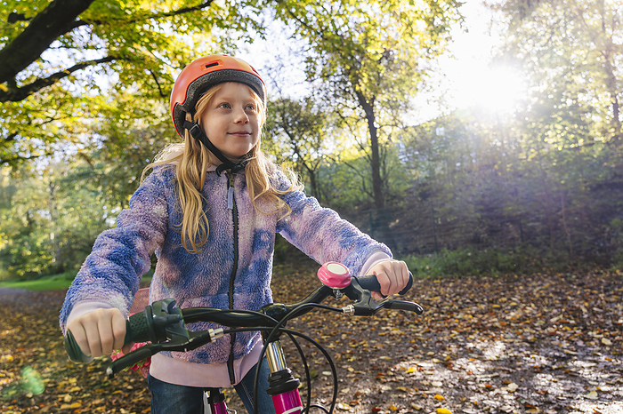 Girl cycling at park on sunny day