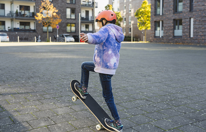 Girl wearing helmet doing ollie on skateboard