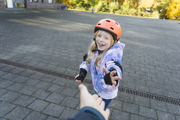 Happy girl wearing helmet giving high-five to mother