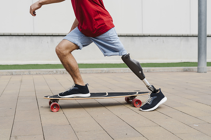 Man with prosthetic leg riding skateboard at footpath