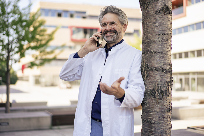 Happy doctor gesturing and talking on mobile phone