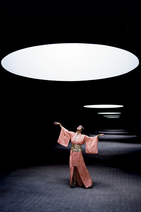 Woman wearing kimono and looking up at spotlight