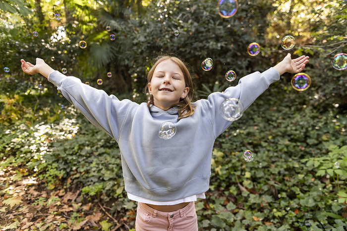 Smiling girl with arms outstretched standing in park