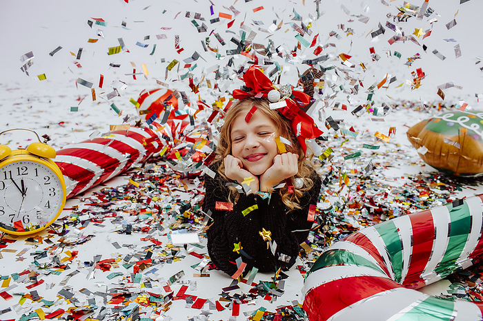 Smiling girl lying near Christmas decoration on floor