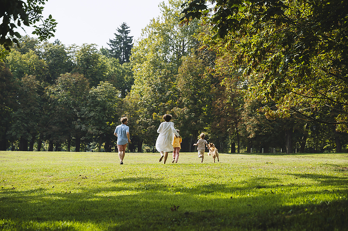 Family enjoying with dog running on grass at park
