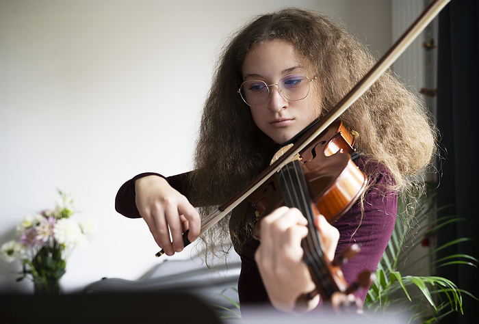 Girl with frizzy hair playing violin at home